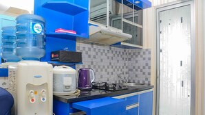 A kitchen with blue cabinets, a water dispenser, a coffee maker, and a stove. - Spacious and Comfy 2BR Bassura City Apartment (Jakarta)