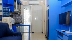 A compact kitchen with a water dispenser, a stove, and a refrigerator. - Spacious and Comfy 2BR Bassura City Apartment (Jakarta)