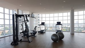 A spacious gym with large windows, exercise equipment, and a city view. - Modern Studio Apartment at Tree Park Cikokol (Tangerang)