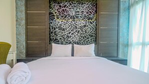 Een net opgemaakt bed met witte lakens en kussens, een decoratief paneel en een raam met gordijnen.
