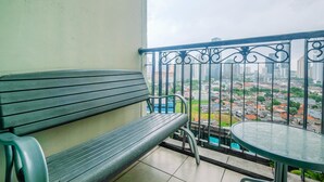 Een balkon met een metalen hekwerk, een groene bank en een kleine tafel.