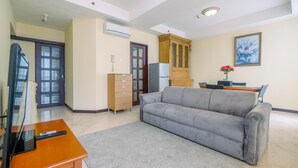 Een woonkamer met een grijze bank, een houten kast en een televisie op een houten tafel.