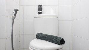 A white toilet with a shower hose and a towel on top. - Pleasant 2BR Apartment at Gateway Ahmad Yani (Bandung)