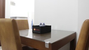 Un salón de conferencias con una mesa de madera, dos sillas marrones y una caja negra con el rótulo 'Travelio' que contiene agua embotellada.