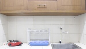 Una cocina con un lavamanos, un escurreplatos y un electrodoméstico rojo.
