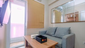 Un salón moderno con un sofá gris, una mesa de madera y una caja negra con la etiqueta 'travelio'.