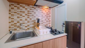 Una cocina con un lavaplatos de acero inoxidable, una estufa a gas y un refrigerador.