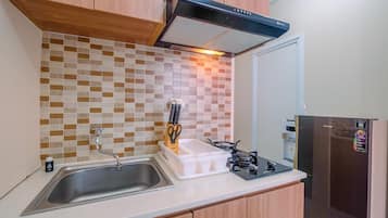 Una cocina con un lavaplatos de acero inoxidable, una estufa a gas y un refrigerador.