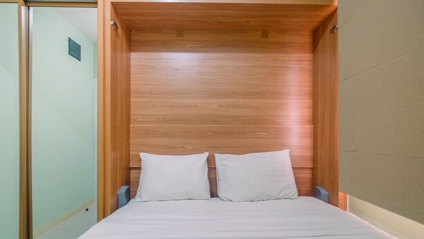 Una cama con cabecera de madera, ropa de cama blanca y una mesita de noche.