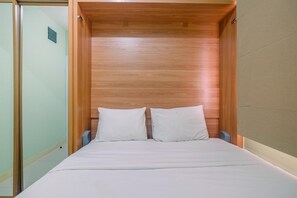 A bed with a wooden headboard, white bedding, and a small bedside table. - Trendy Connecting Mall 2BR Green Pramuka Apartment (Jakarta)