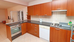 A kitchen with wooden cabinets, a built-in oven, a dishwasher, and a coffee maker. - Apartments Villa Michele (Orebic)