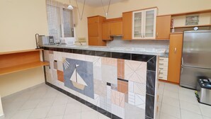 A modern kitchen with a marble island, wooden cabinets, and a stainless steel refrigerator. - Apartments Villa Michele (Orebic)