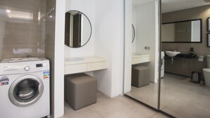 A modern bathroom with a washing machine, a mirror, a sink, and a toilet. - Premium 2BR Apartment near Marvell City Mall at The Linden (Surabaya)