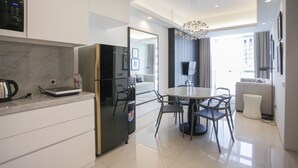 A modern kitchen with a refrigerator, stove, and dining area with chairs and a table. - Premium 2BR Apartment near Marvell City Mall at The Linden (Surabaya)