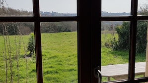 Una habitación con ventanas amplias que ofrecen vistas a un campo verde y colinas lejanas.