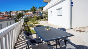 A balcony with a table and chairs, overlooking a residential area with houses and greenery. - Apartments Magdales (Dugi Rat)