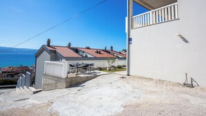 A residential building with a balcony, a patio with outdoor furniture, and a view of the sea. - Apartments Magdales (Dugi Rat)