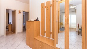 A room with a wooden wardrobe, a bench, and a mirror. There is a door leading to another room, and a small table with a telephone and a clock. - Apartments Magdales (Dugi Rat)
