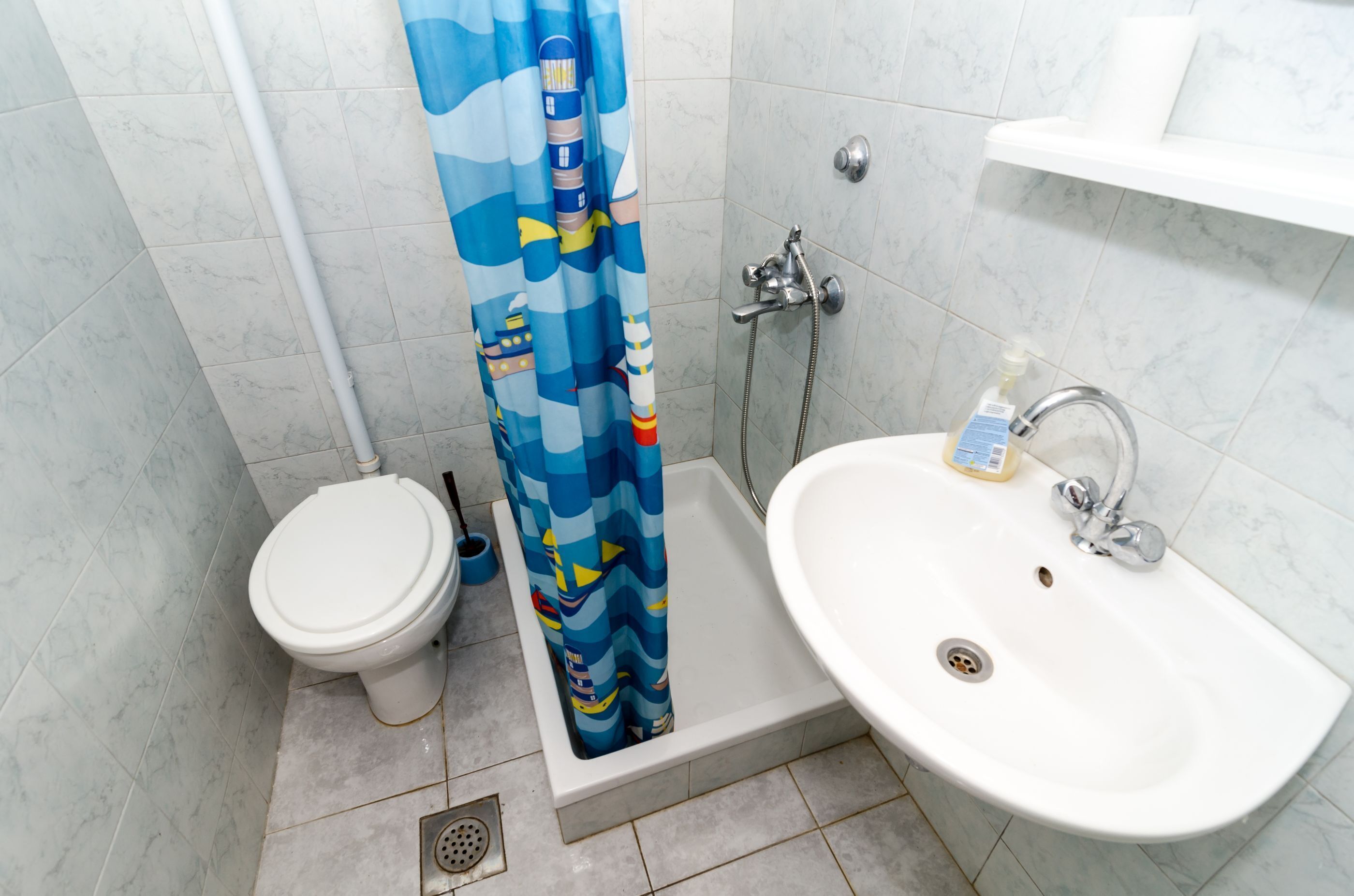 A bathroom with a toilet, shower, and sink.