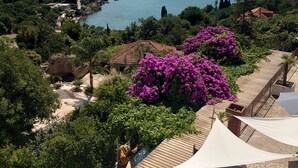 Propiedad costera con vista al mar, rodeada de vegetación y una terraza de madera.