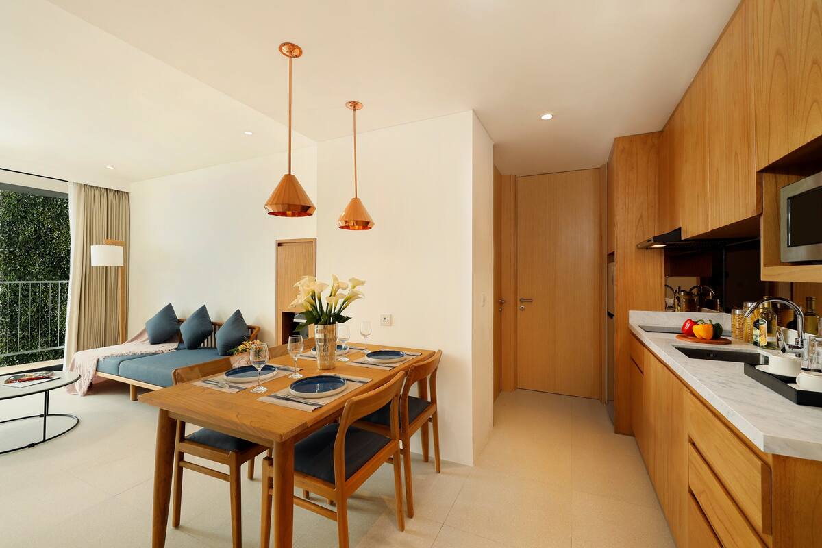 Een moderne keuken met houten kastjes, een eettafel met stoelen en hanglampen.