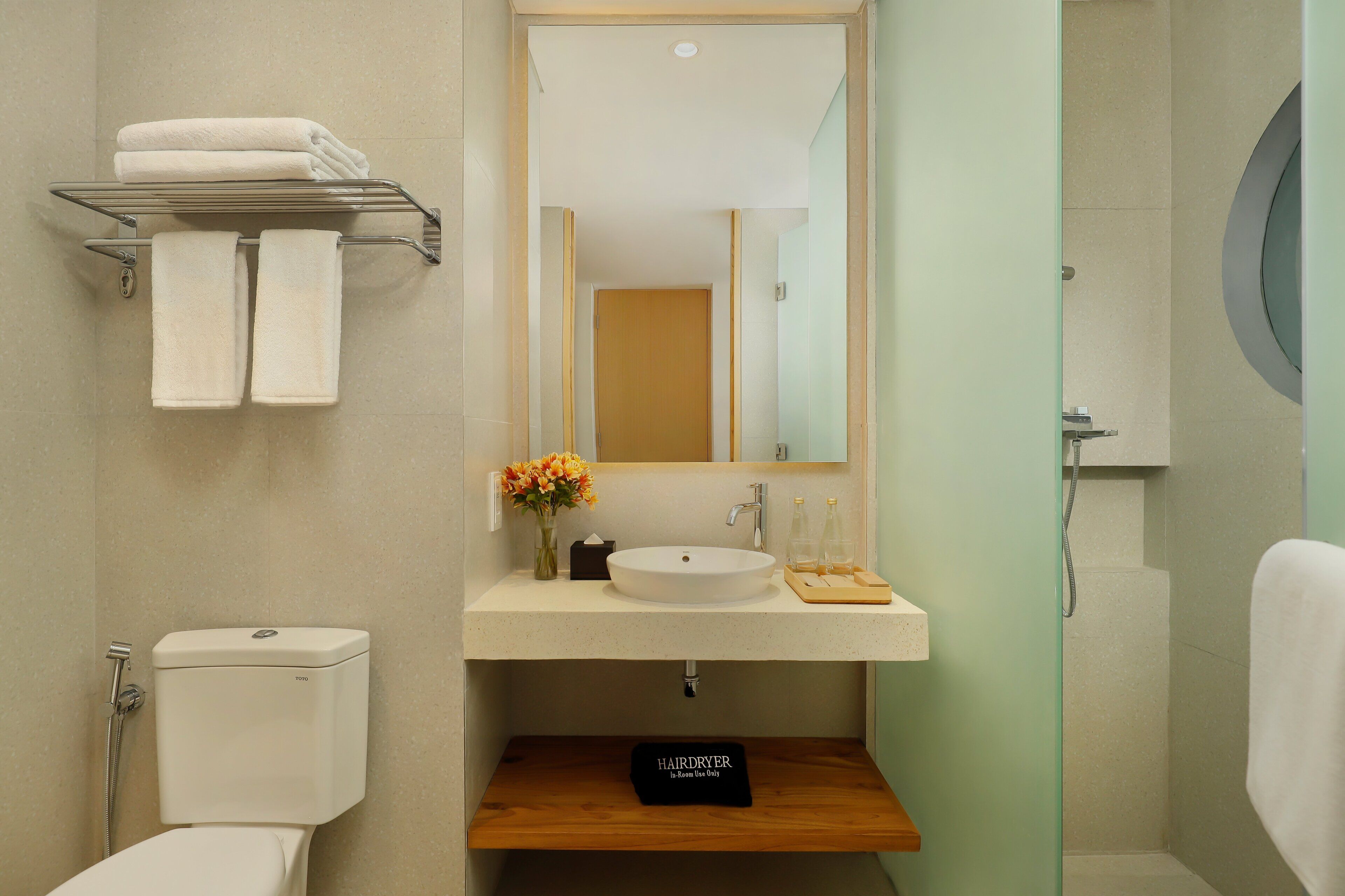 A bathroom with a toilet, a sink with a mirror, a towel rack, and a hairdryer.