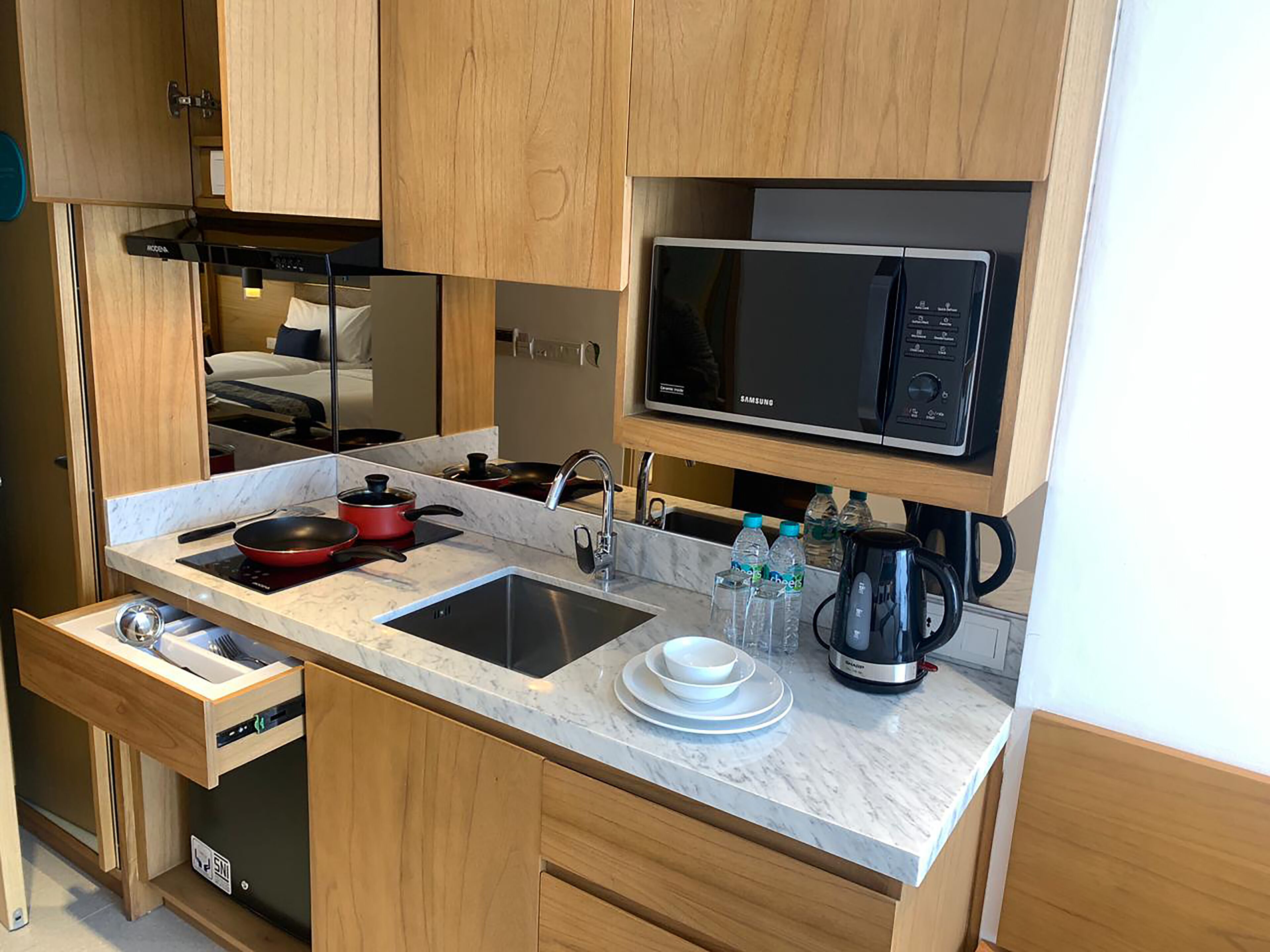 A compact kitchenette with a microwave, stove, sink, and storage cabinets.