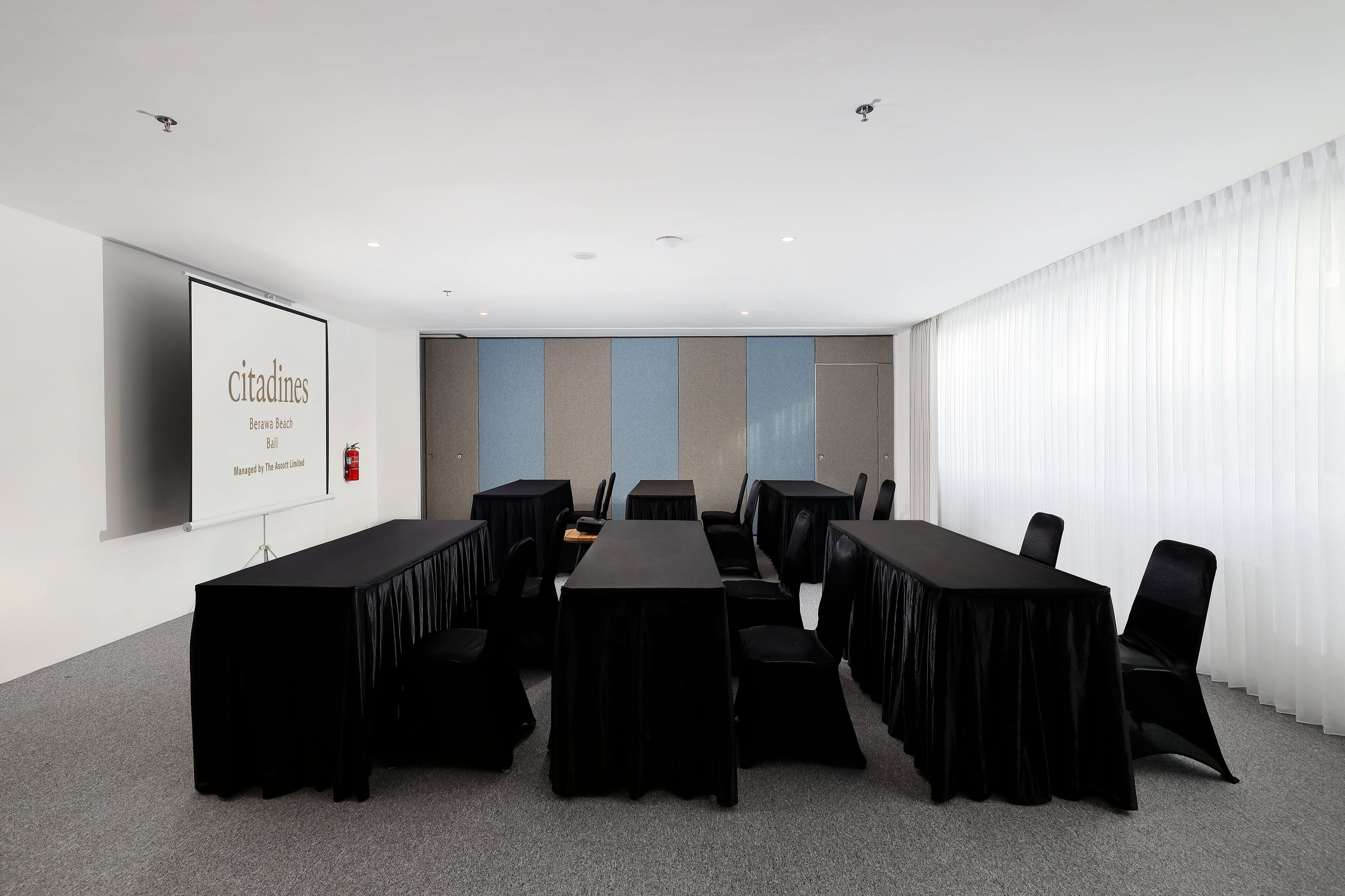 A conference room with a long table, black chairs, and a projector screen displaying 'citadines'.