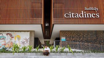En byggnad med en skylt som visar namnet ”Citadines”, en väggmålning och en person som sitter på en bänk.