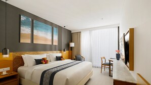 A modern hotel room with a large bed, a desk, and a TV. - Citadines Berawa Beach Bali Resort (Canggu)