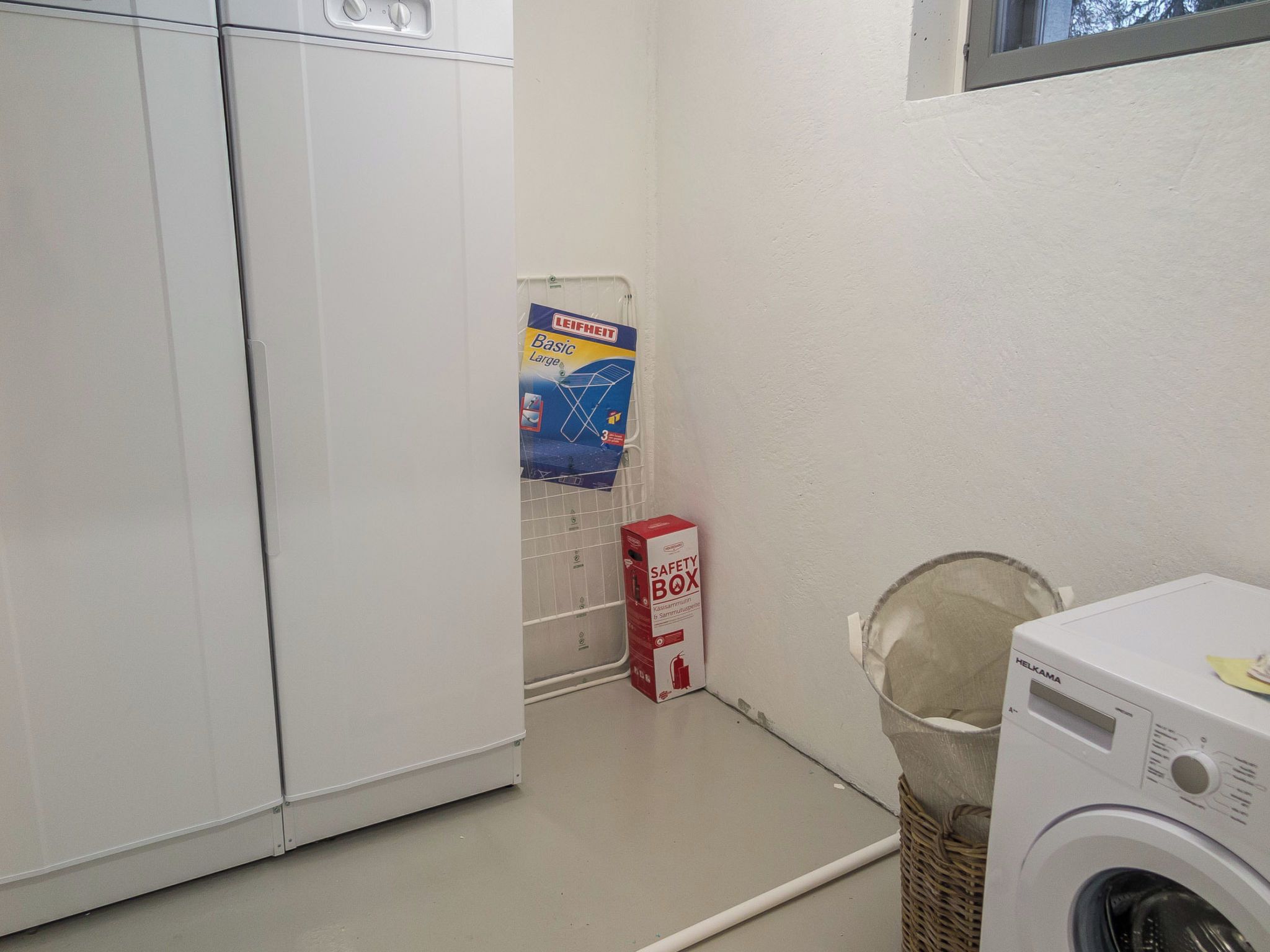 Een wasserette met een wasmachine, een kluisje en een Leifheit product aan de muur.