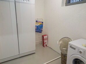 Une buanderie équipée d’un lave-linge, d’un coffre-fort et d’un produit Leifheit fixé au mur.