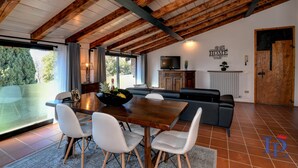 A dining area with a wooden table and white chairs, a black sofa, and a television on the wall. - Desenzanoloft Swarovski (Desenzano del Garda)