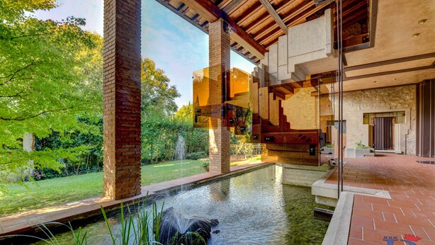 A modern building with a glass atrium, a water feature, and a brick exterior. - Desenzanoloft Swarovski (Desenzano del Garda)