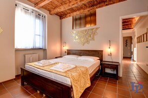 Un letto rifatto con cura, con una coperta a fantasia, una testiera in legno e un elemento decorativo a parete.
