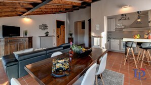 A modern kitchen with white cabinets, a wooden countertop, and a dining area with a wooden table and chairs. - Desenzanoloft Swarovski (Desenzano del Garda)