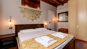 A hotel room with a large bed, a wooden headboard, a decorative wall piece, and a wardrobe. - Desenzanoloft Swarovski (Desenzano del Garda)