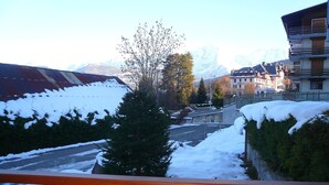 Ein verschneites Bergstädtchen mit Blick auf eine Straße, die zu einem Gebäude mit Balkon führt.