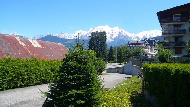 Ein Wohngebiet mit Blick auf schneebedeckte Berge, einer asphaltierten Straße und einem Gebäude mit Balkonen.