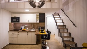 Et moderne køkken med en central ø, indbygget mikroovn og en trappe til et højere niveau.