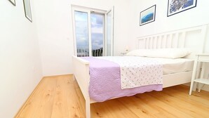 Ein Schlafzimmer mit Bett, Fenster und einem weißen Kopfteil.