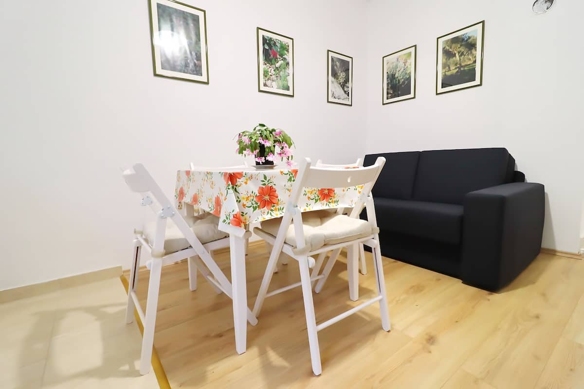 A dining area with a table and chairs, a black sofa, and framed pictures on the wall.