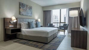 A modern hotel room with a large bed, bedside lamps, a desk, a chair, a flat-screen TV, and a large window with curtains. - Residence Inn by Marriott Algiers Bab Ezzouar (Algiers)