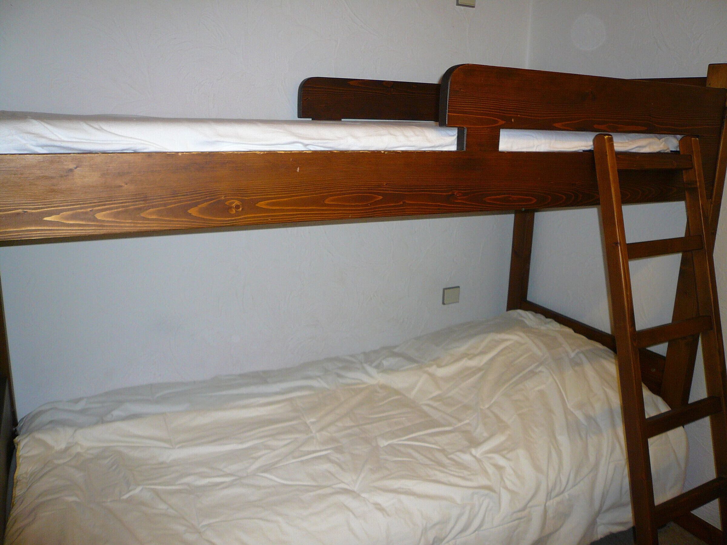 Uma cama beliche com estrutura de madeira e colchão.