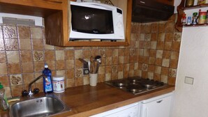 Een keuken met een magnetron, spoelbak, kookplaat en vaatwasser.