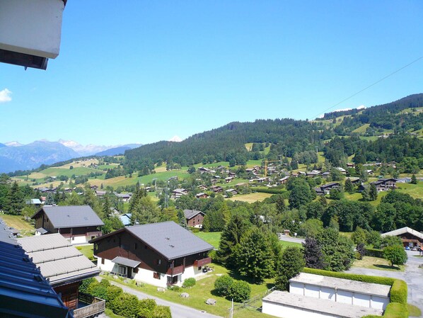 A rural village with traditional houses, a clear sky, and mountains in the background.