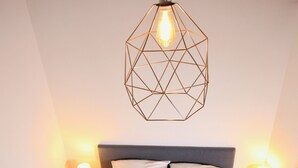 A neatly made bed with a patterned throw, two bedside lamps, and a geometric light fixture above. - "Tigny House", private chalet in the heart of Valloire, 4 to 6 persons (Valloire)