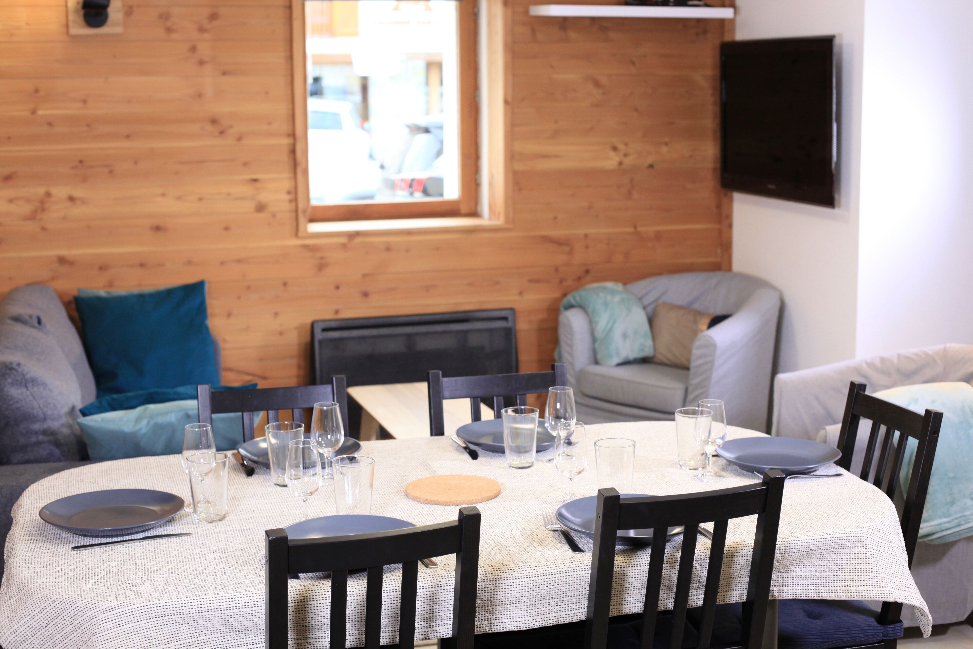 A dining area with a round table set for four, surrounded by wooden chairs.