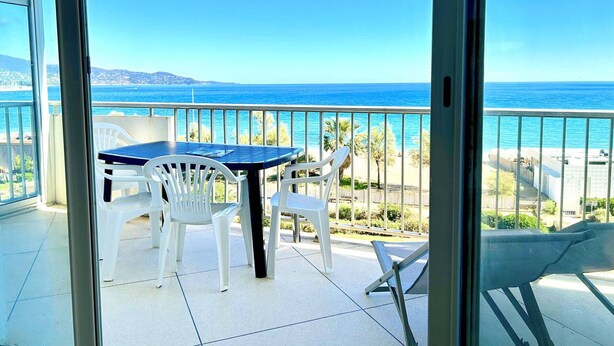 Ein Balkon mit Tisch und Stühlen mit Blick auf einen Strand und den Ozean.