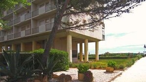 Ein mehrstöckiges Hotel mit überdachtem Außenbereich, umgeben von begrünten Gärten und einem Kiesweg.